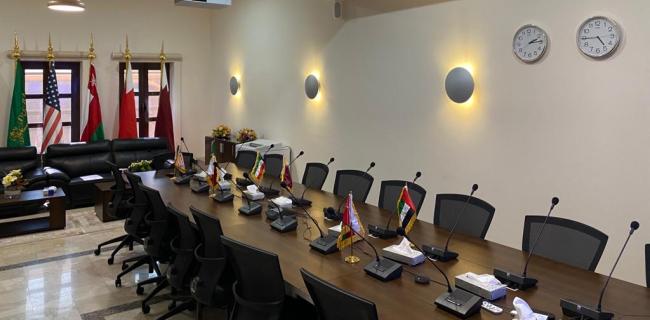 Conference room with table, chairs. Flags are displayed on tables and on flag poles.